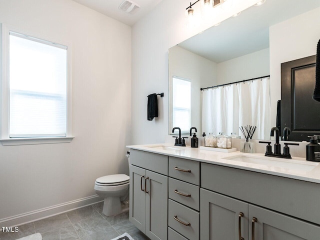 full bath with double vanity, baseboards, visible vents, and a sink