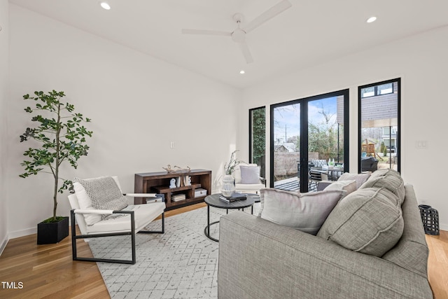 living room featuring light wood-style flooring, baseboards, ceiling fan, and recessed lighting