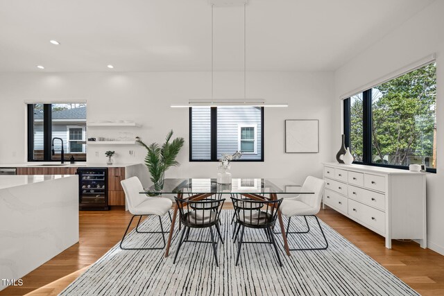 dining area with a wealth of natural light, beverage cooler, light wood-style flooring, and recessed lighting