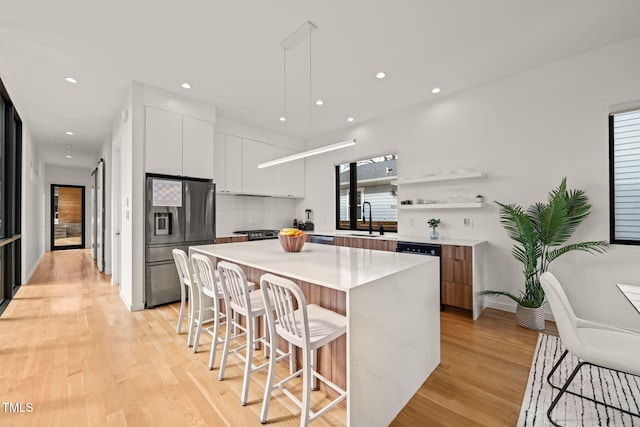 kitchen with a kitchen breakfast bar, modern cabinets, a sink, and stainless steel fridge with ice dispenser