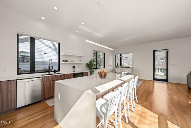 kitchen with brown cabinets, stainless steel dishwasher, a kitchen island, a sink, and modern cabinets