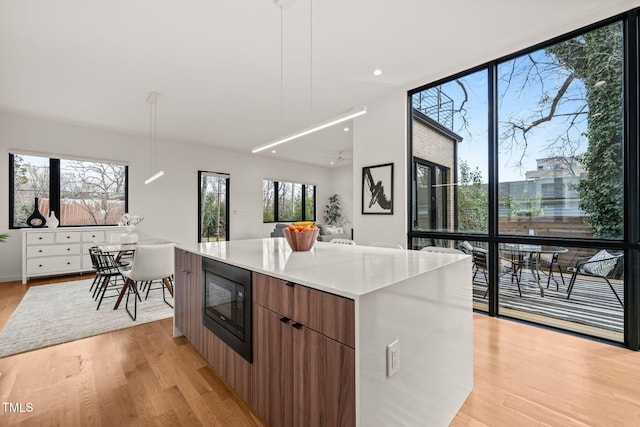 kitchen featuring black microwave, modern cabinets, a kitchen island, and light wood-style flooring