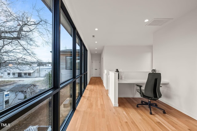 office featuring visible vents, baseboards, light wood-style flooring, a wall of windows, and recessed lighting