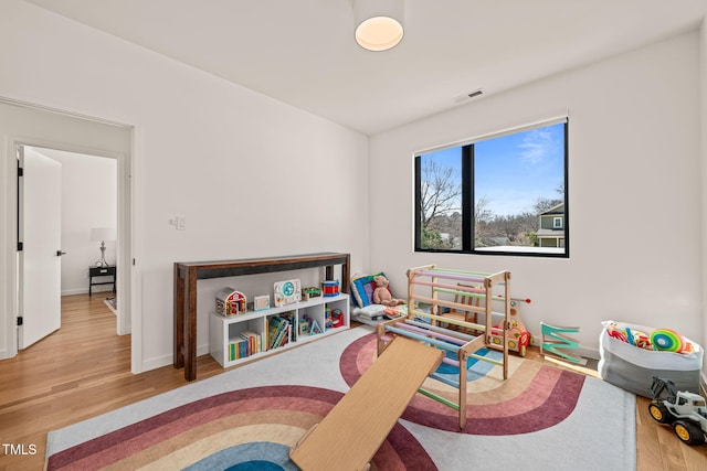 playroom with baseboards, visible vents, and wood finished floors