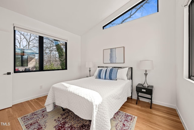 bedroom with multiple windows, vaulted ceiling, and light wood finished floors