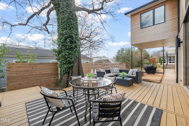 wooden terrace with an outdoor hangout area, outdoor dining space, and fence