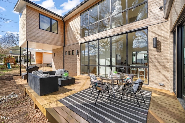 deck featuring outdoor dining area, a playground, and an outdoor living space