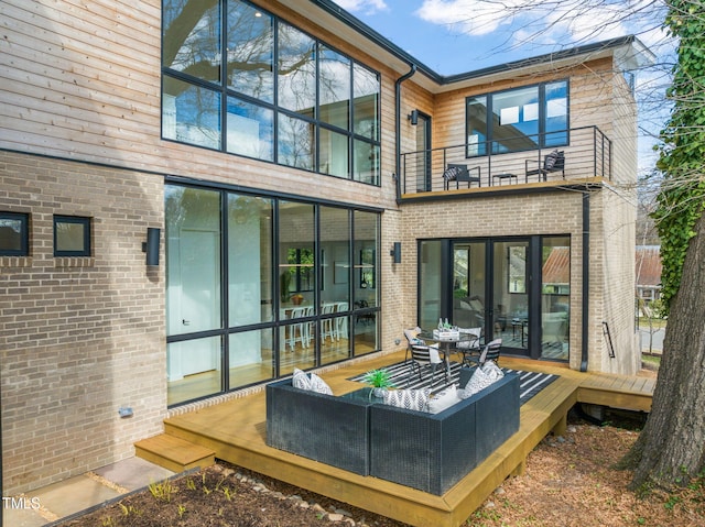 rear view of property featuring a deck, brick siding, and a balcony