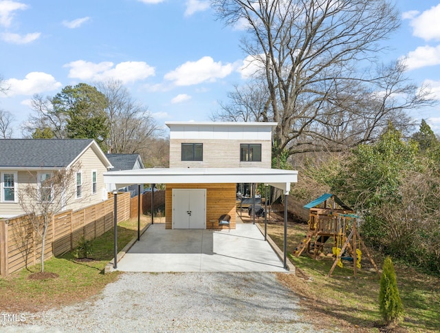 view of front of property with gravel driveway, a playground, and fence