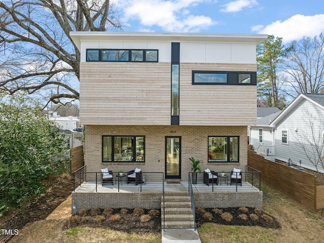 view of front of property with fence, an outdoor hangout area, and brick siding