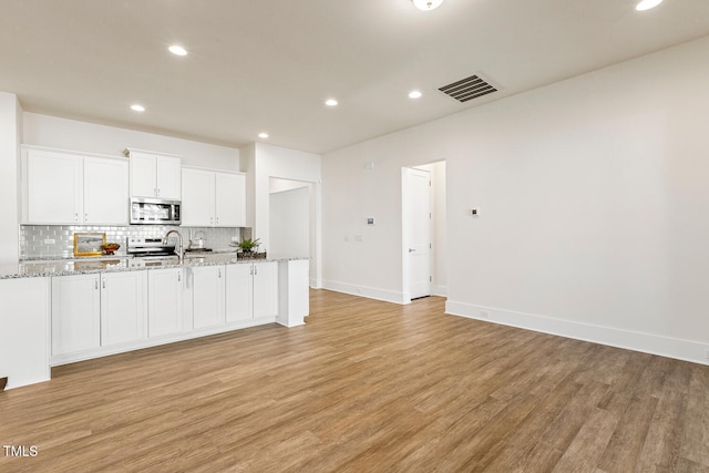 kitchen featuring visible vents, backsplash, appliances with stainless steel finishes, light wood-style floors, and white cabinets