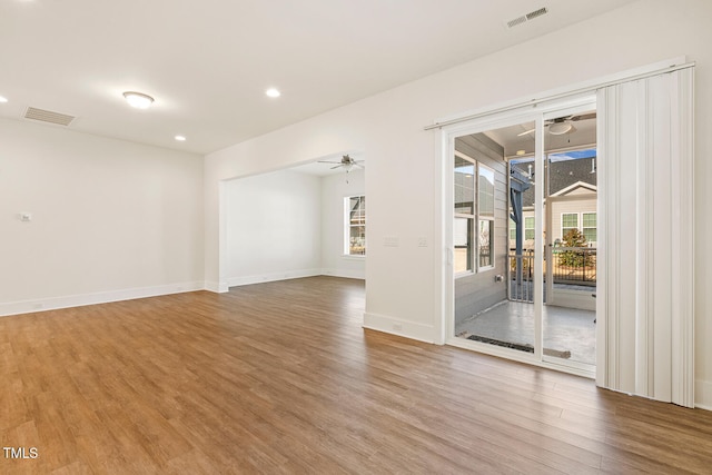 unfurnished room with baseboards, wood finished floors, visible vents, and a ceiling fan