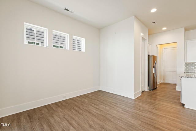 spare room featuring light wood-type flooring, visible vents, baseboards, and recessed lighting