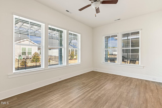 spare room featuring wood finished floors, visible vents, and baseboards