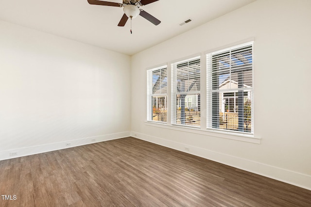 spare room featuring baseboards, visible vents, ceiling fan, and wood finished floors