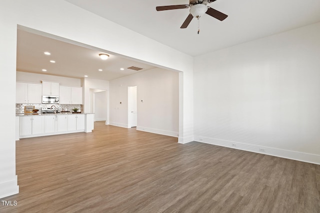 unfurnished living room with light wood-type flooring, baseboards, a ceiling fan, and recessed lighting