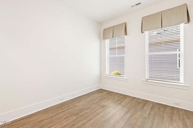 empty room featuring light wood-style flooring, visible vents, and baseboards