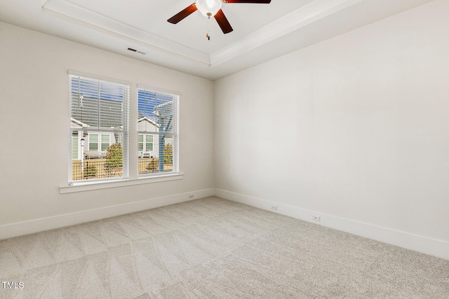 spare room with visible vents, baseboards, a ceiling fan, a tray ceiling, and carpet floors