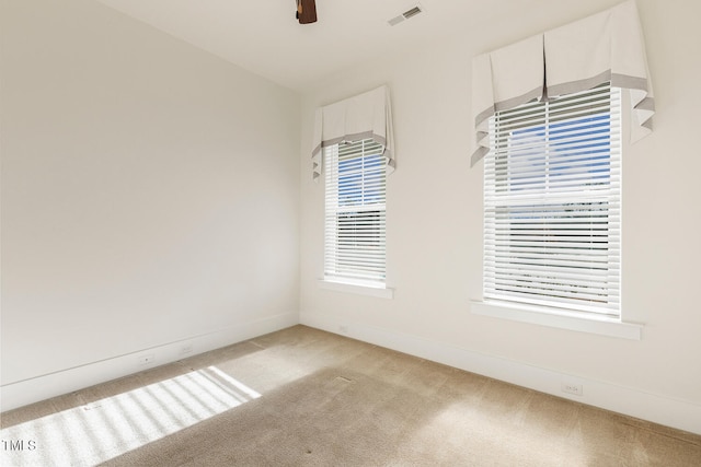 spare room featuring light carpet, baseboards, visible vents, and a ceiling fan