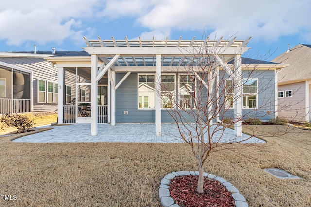 rear view of property featuring a lawn, a patio area, a sunroom, and a pergola