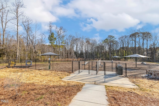 view of community with a gate, fence, and a view of trees