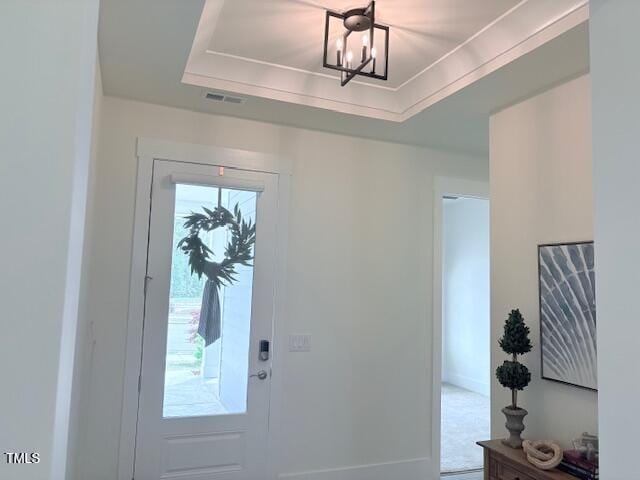 foyer entrance featuring an inviting chandelier, a tray ceiling, and visible vents