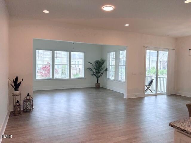 unfurnished living room with baseboards, wood finished floors, and recessed lighting