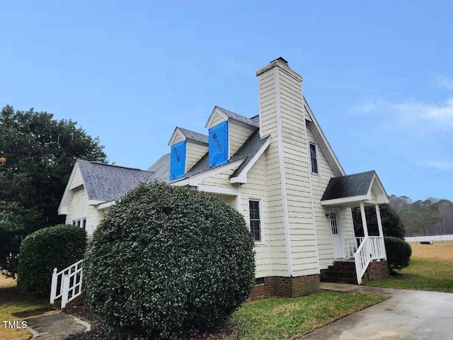 view of home's exterior with a shingled roof, crawl space, and a chimney