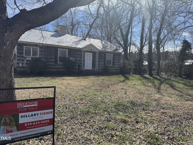 view of front of property featuring a chimney and a front yard