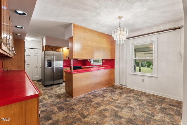 620 Mcghees Mill Rd, Roxboro, NC 27574 - kitchen with a notable chandelier, stainless steel fridge with ice dispenser, brown cabinetry, a peninsula, and baseboards