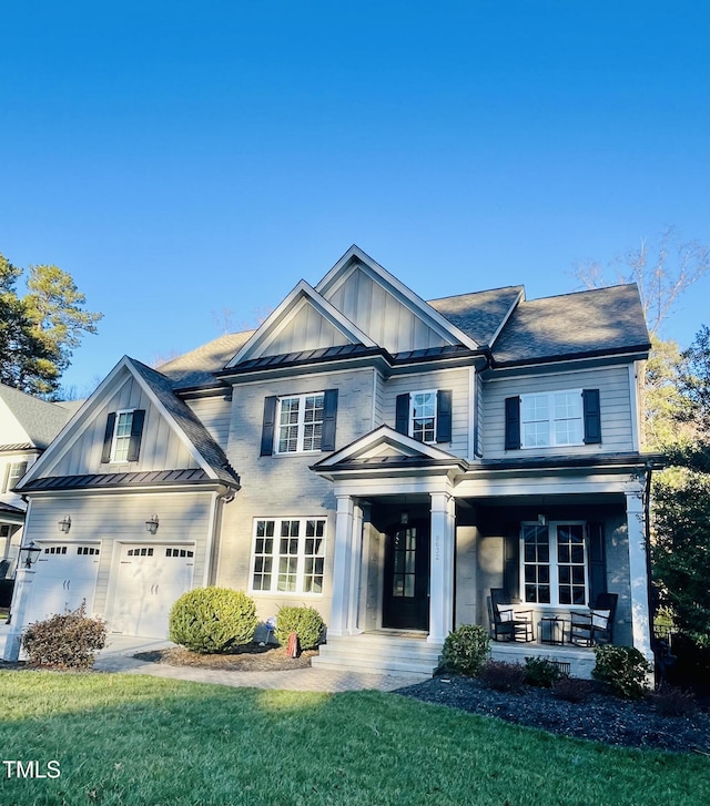 view of front of home featuring an attached garage, a standing seam roof, a front lawn, a porch, and board and batten siding