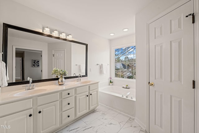 full bathroom with marble finish floor, double vanity, a sink, and a bath