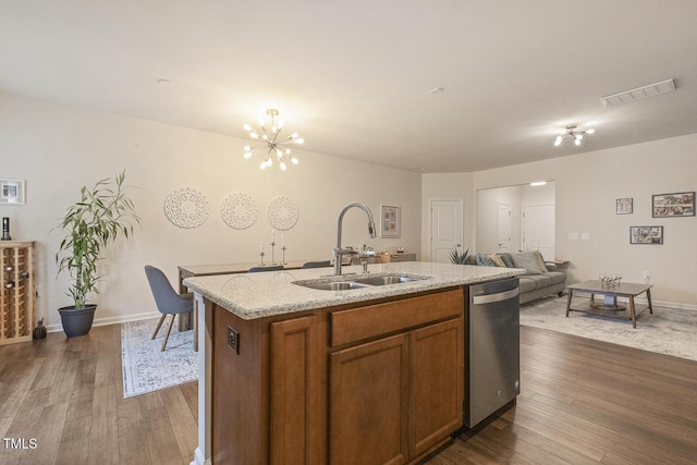 kitchen with visible vents, dark wood finished floors, dishwasher, brown cabinets, and a sink