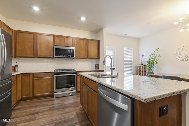 kitchen with appliances with stainless steel finishes, dark wood-style flooring, a sink, and brown cabinets