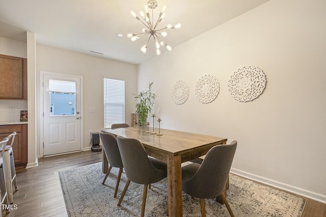 dining area featuring dark wood-style floors, a chandelier, and baseboards