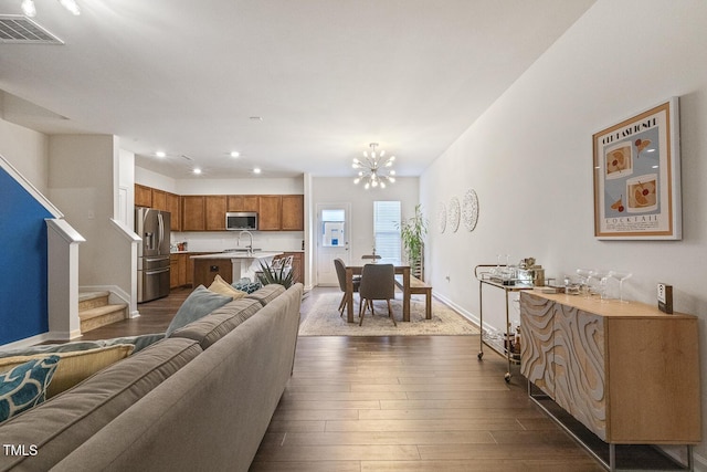 living room featuring baseboards, visible vents, dark wood finished floors, an inviting chandelier, and stairs