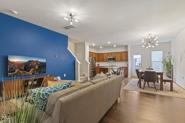 living area with baseboards, visible vents, stairway, dark wood-type flooring, and a notable chandelier