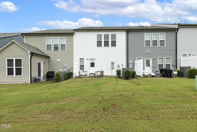 back of property with central AC and a lawn