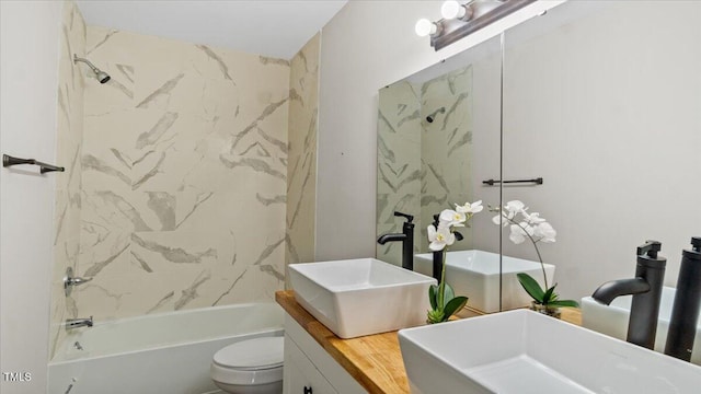 bathroom featuring double vanity, a sink, toilet, and shower / bathtub combination