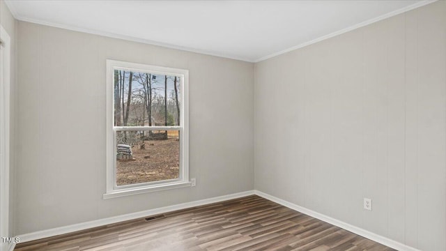 empty room with baseboards, visible vents, wood finished floors, and ornamental molding