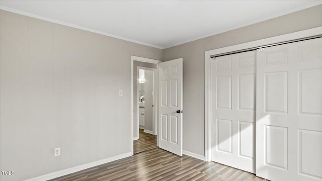 unfurnished bedroom featuring a closet, crown molding, baseboards, and wood finished floors