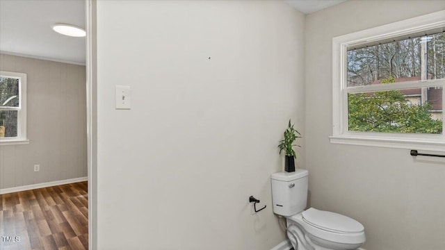 bathroom with toilet, baseboards, and wood finished floors