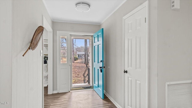 entrance foyer with baseboards, crown molding, visible vents, and wood finished floors