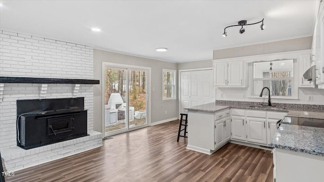 kitchen with a kitchen bar, light stone counters, white cabinets, and a sink