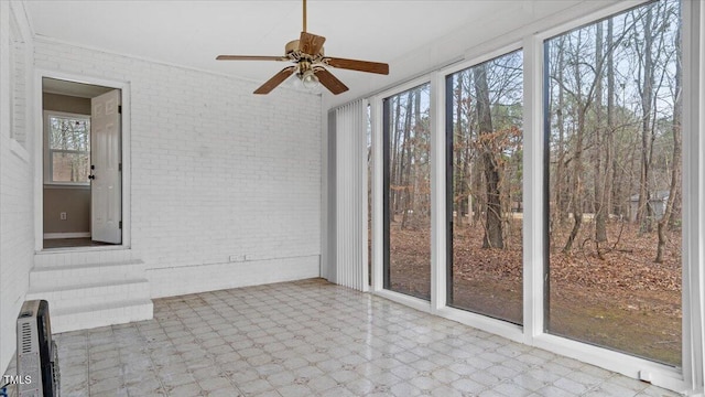 unfurnished sunroom featuring ceiling fan