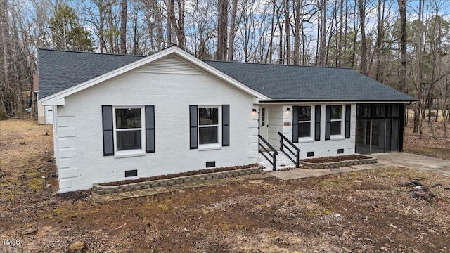 ranch-style home with brick siding, roof with shingles, entry steps, a sunroom, and crawl space