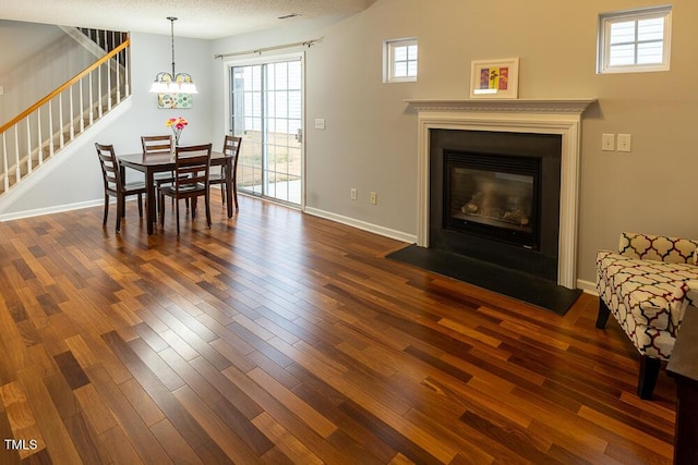 dining space with a glass covered fireplace, stairway, dark wood finished floors, and baseboards