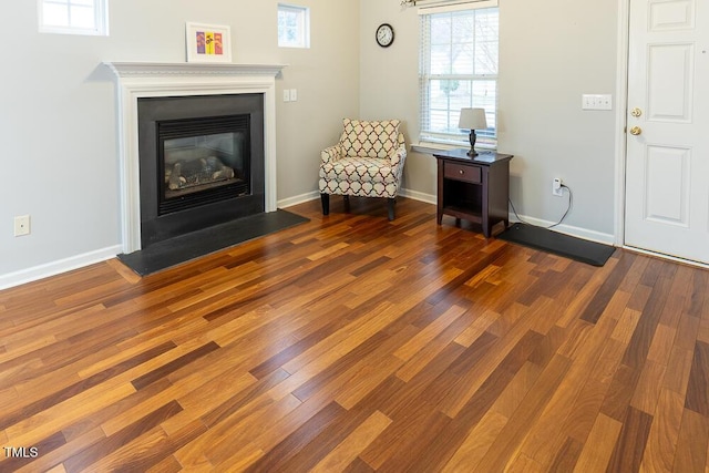 unfurnished room featuring dark wood-style floors, baseboards, and a glass covered fireplace