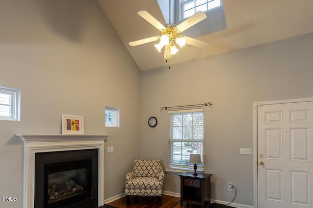 sitting room with high vaulted ceiling, a glass covered fireplace, baseboards, and a ceiling fan