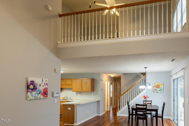 kitchen with decorative light fixtures, light countertops, a sink, a textured ceiling, and a peninsula